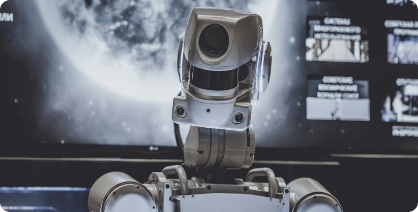 A photo of a robot with computers and a big screen with the moon in the background.