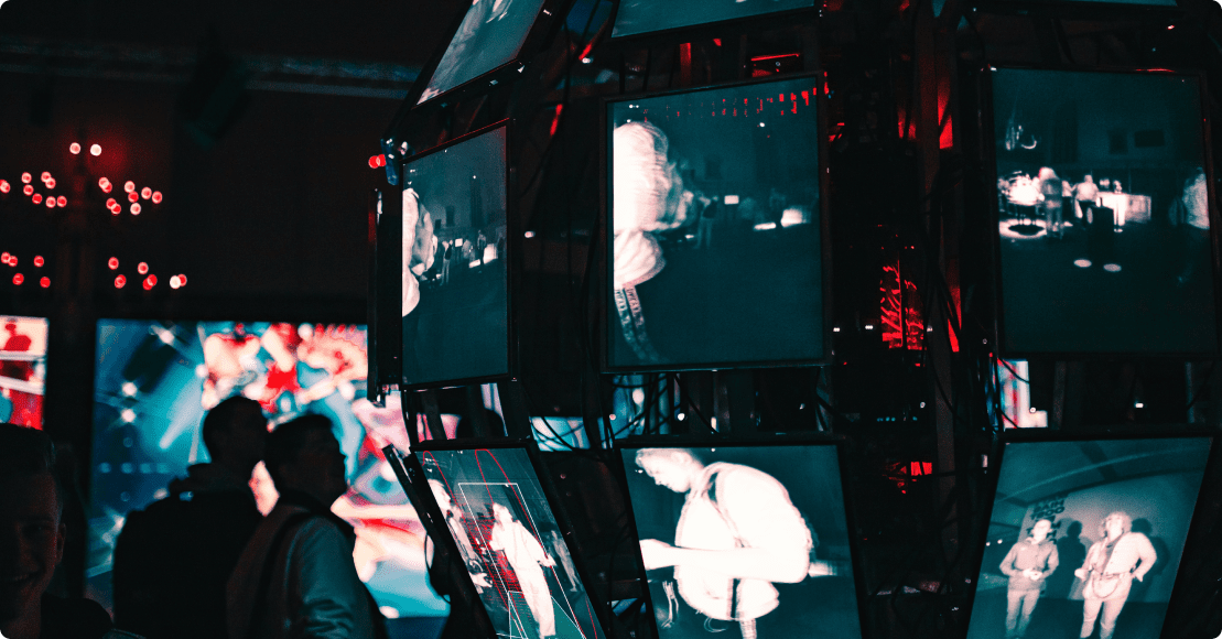 A photograph of a many screens and people watching them. A science tech exhibition.